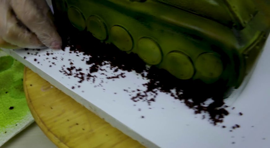 Торт танк: Крошим обрезки шоколадного бисквита, и присыпаем основание у гусениц танка получившейся землёй. На этом торт готов.