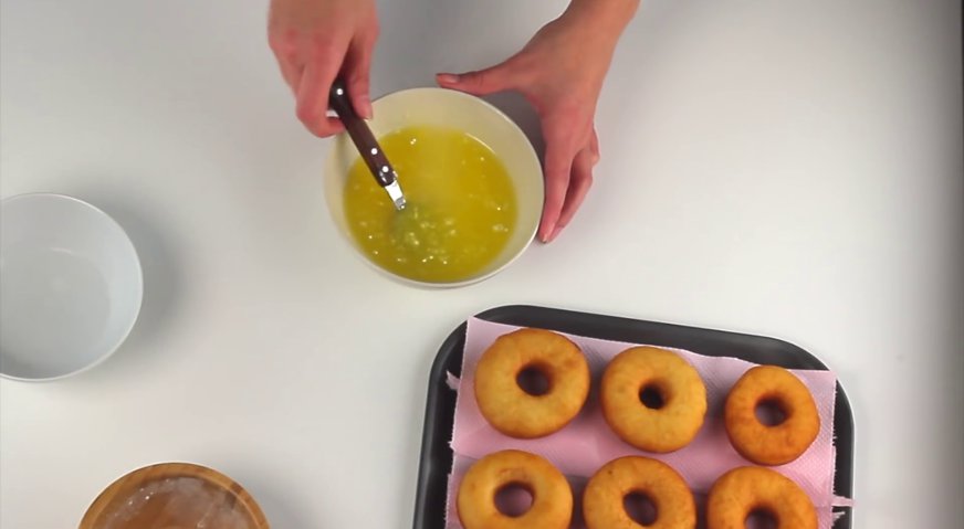 Классические пончики: Готовим глазурь. Для этого в несколько приёмов смешиваем растопленное сливочное масло с водой и сахарной пудрой.