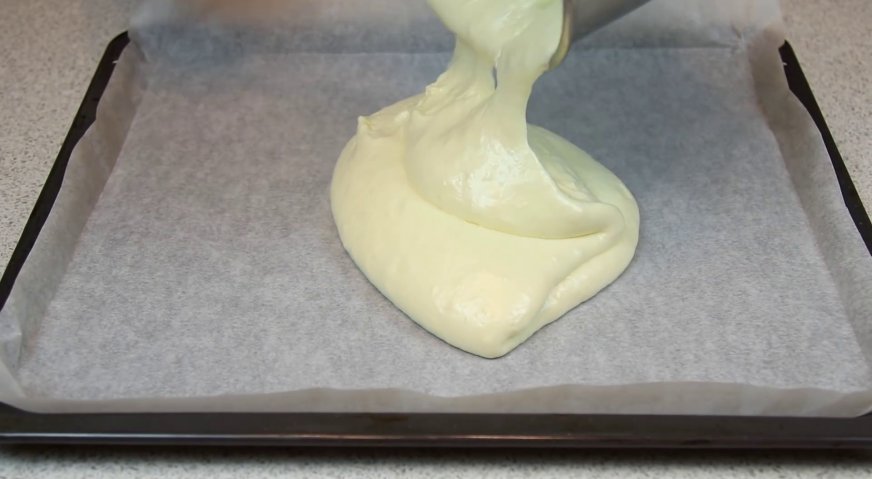 Пирожное картошка: Готовое бисквитное тесто выливаем на противень, застеленный пергаментом, и распределяем по всей поверхности.