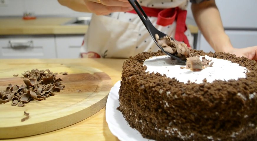 Торт черный принц: Поверхность торта покрываем сметанным кремом, бока посыпаем бисквитной крошкой, а сверху выкладываем тёртый шоколад.