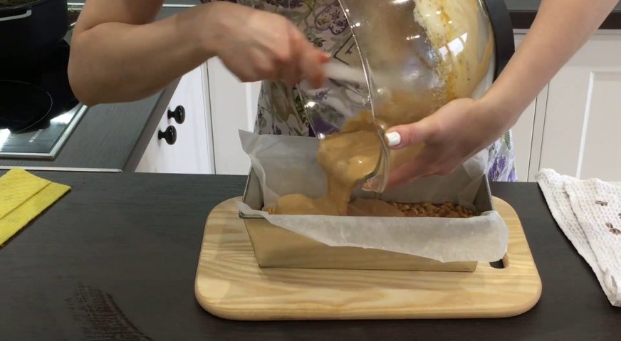 Торт сникерс: Выливаем нугу в форму на орехи с карамелью, распределяя равномерным слоем.