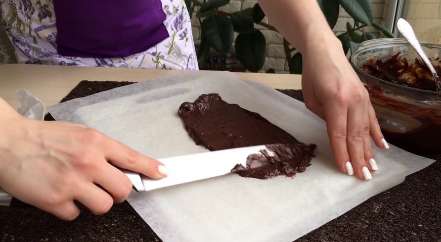 Торт сникерс: На лист пергамента выкладываем немного ганаша, и разравниваем ножом равномерным слоем по размеру нашего торта.