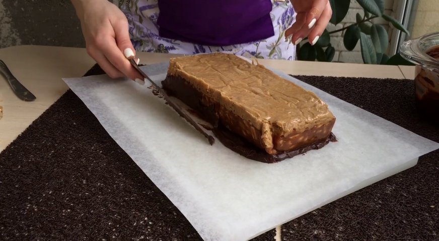 Торт сникерс: Ганаш, выходящий за периметр начинки, заворачиваем ножом на края орехово-карамельного бруска.