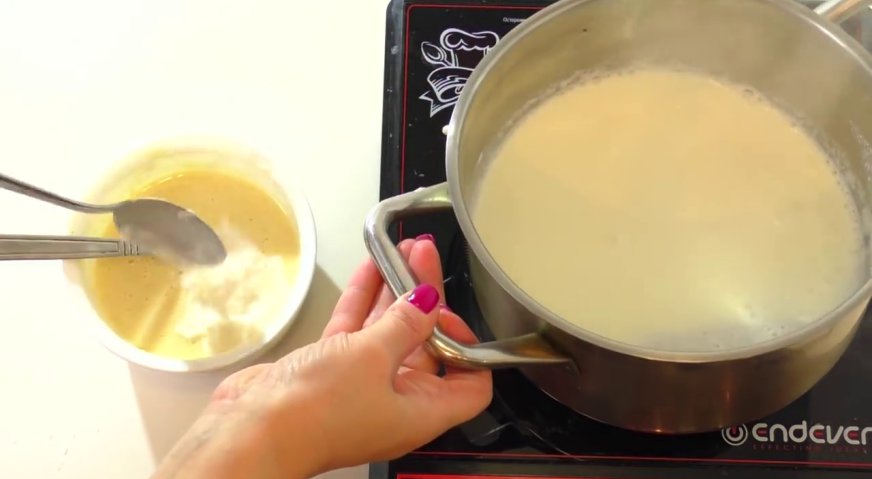 Крем пломбир для торта: Ставим молоко на огонь, и когда оно закипит, добавляем немного горячего молока в яично-крахмальную смесь.