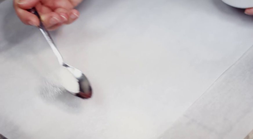 Торт слеза слона: Чистый лист пекарской бумаги посыпаем сахаром, и переворачиваем на неё бисквит.